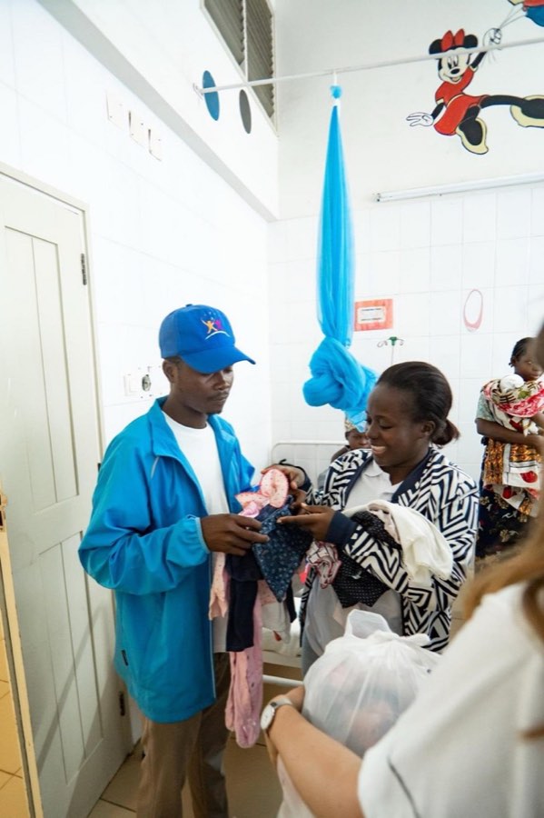A Goodwill team member handing a gift to a new mother and her baby