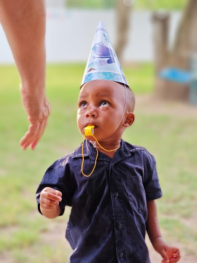 A young child being fed by a volunteer at Goodwill